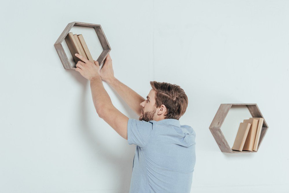 image of a man hanging trending octaganol shelving with a stud finder