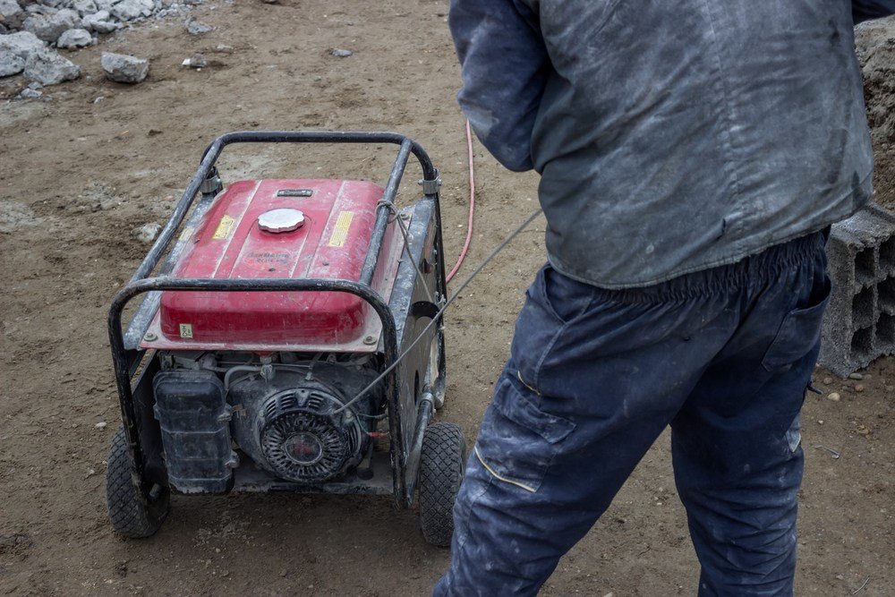 image of man starting dirty generator on building site