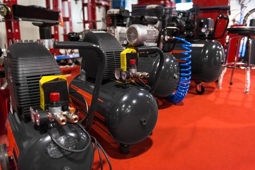 image of black air compressors for sale against red floor