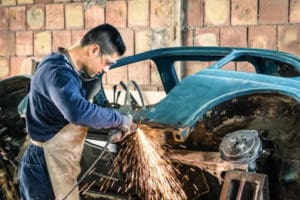 mechanic working on car with angle grinder