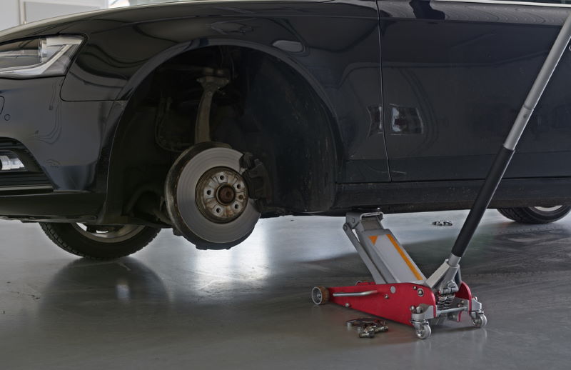 detail of car on car jack with tire removed
