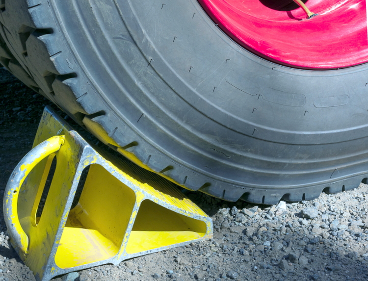 image of a yellow metal wheel chock securing tire